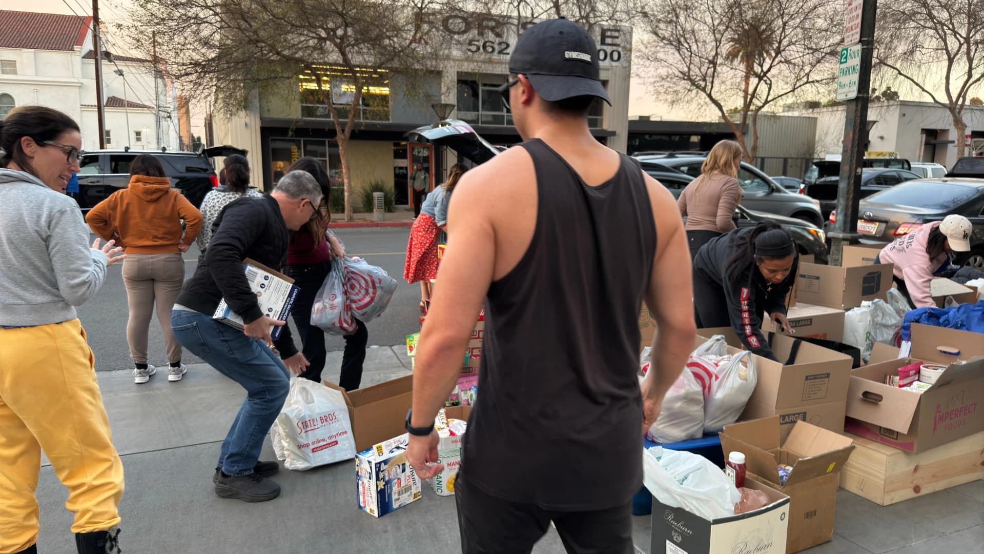 Neighbors sorting donated bags and boxes together on the sidewalk outside RightMealz