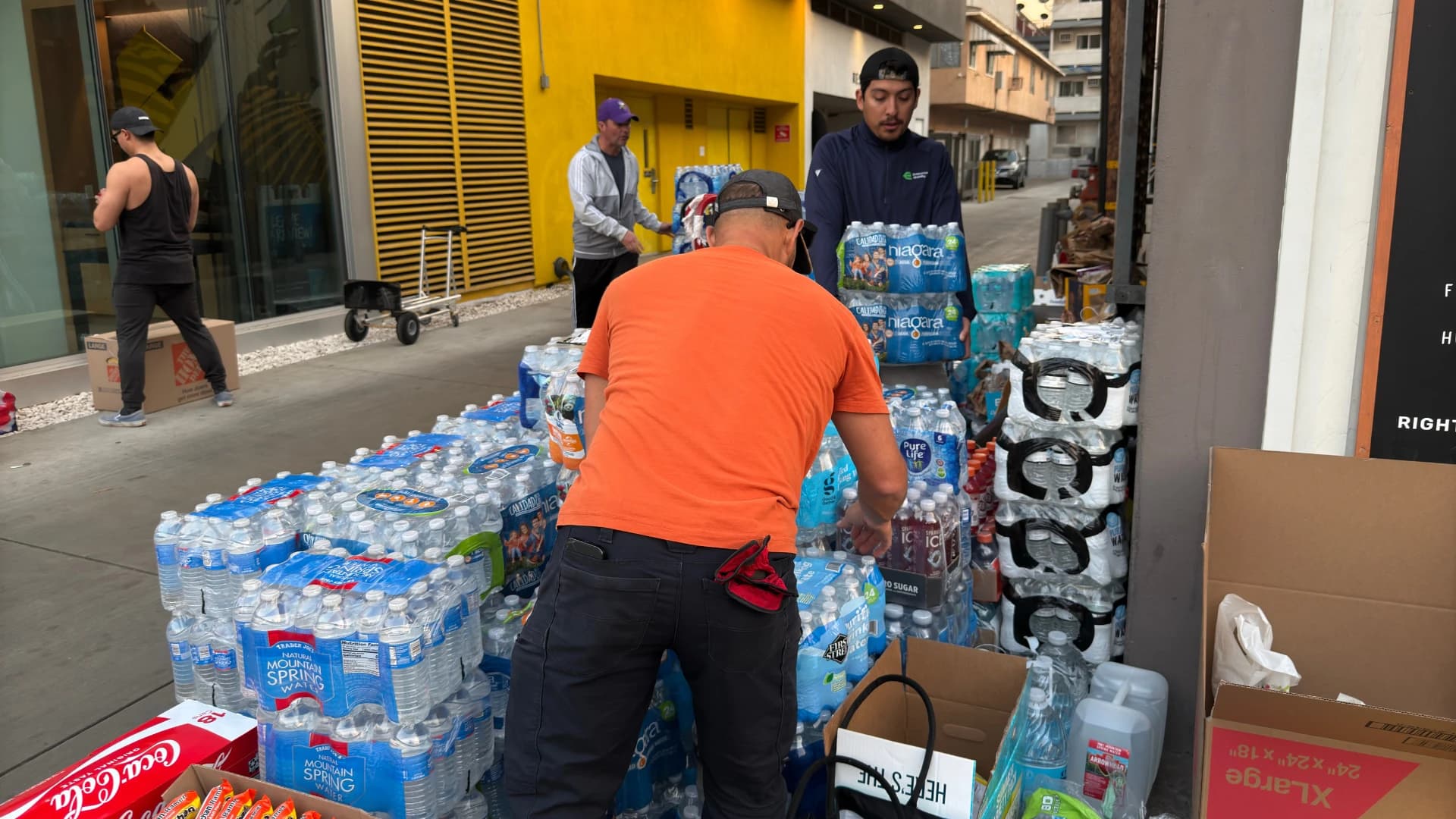 Cases of donated bottled water and supplies stacked outside the RightMealz drive
